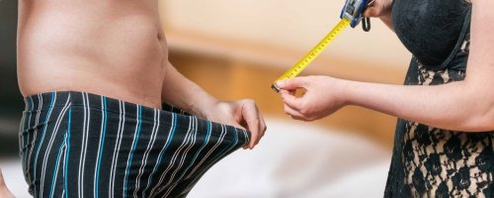 Een vrouw meet de lengte van een man van een lid